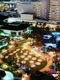 Rushika & Neil, JW Marriot Cancun Mexico, Welcome Party Aerial view of an outdoor evening event with round tables, string lights, and pools at a hotel resort.