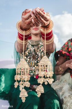 A woman in traditional Indian attire displays her ornate jewelry and henna-decorated hands toward the camera.
